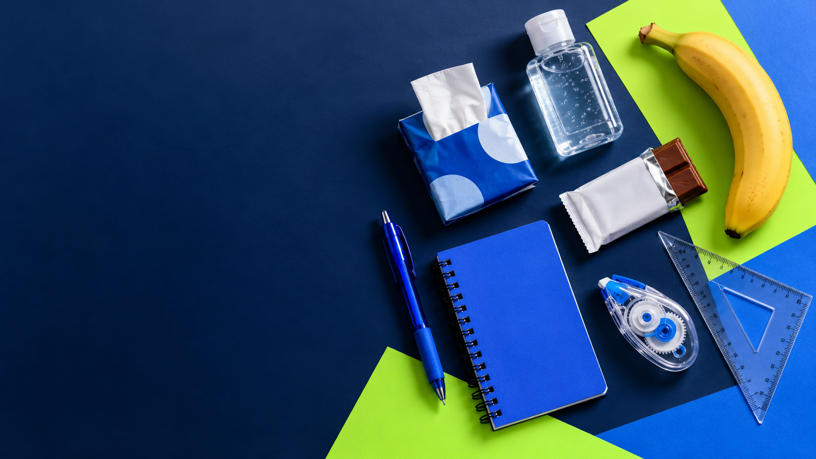 School supplies, hygiene essentials and a snack arranged on a navy surface